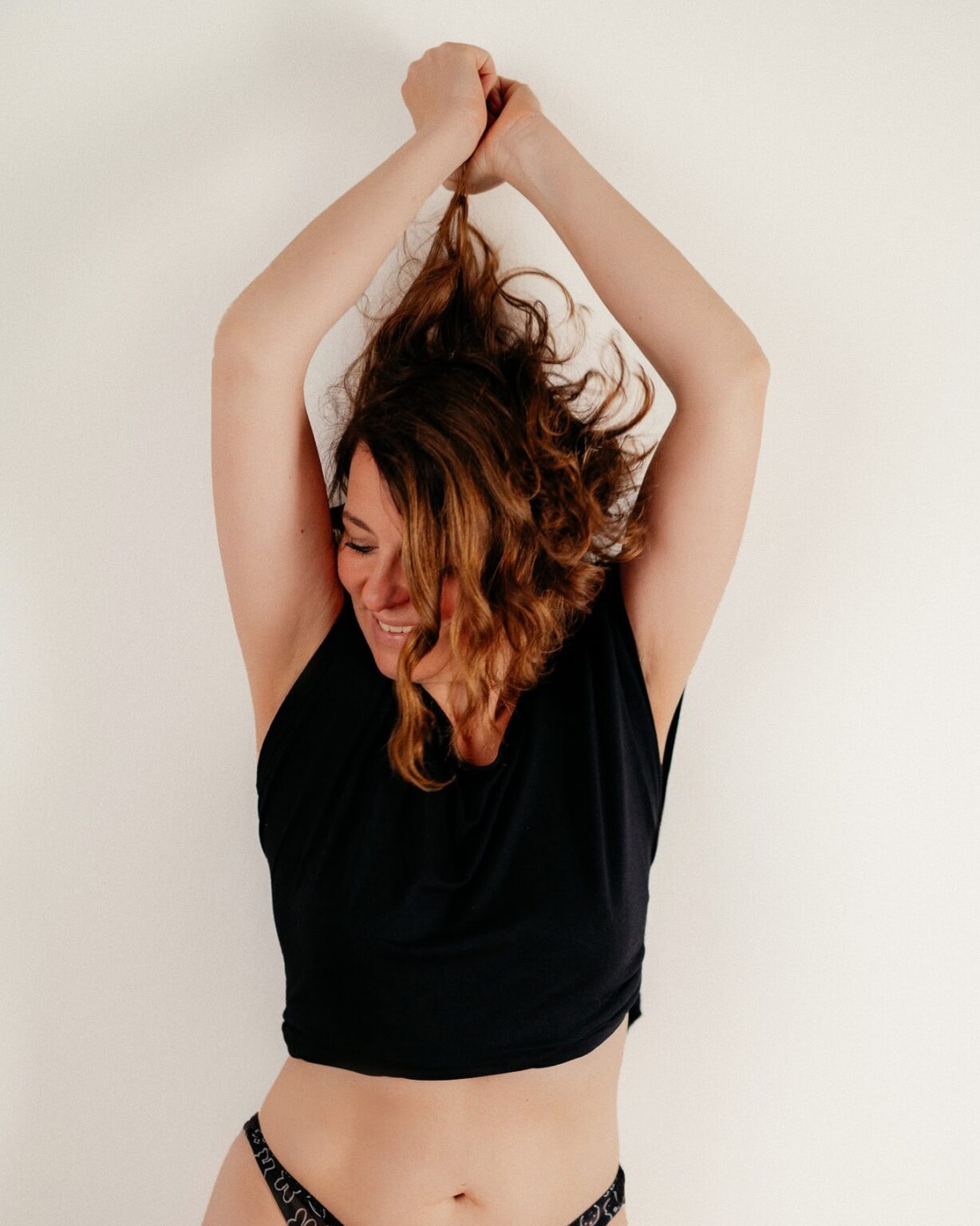 Bild einer lachenden Frau in schwarzem Top und Spitzenhöschen.